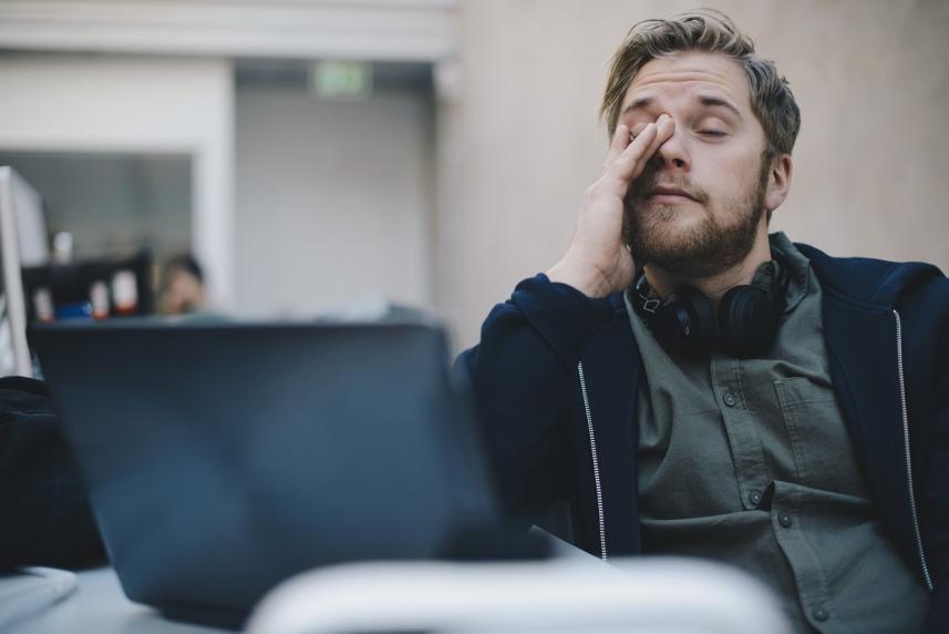 Tired office worker rubbing eyes while staring at computer screen