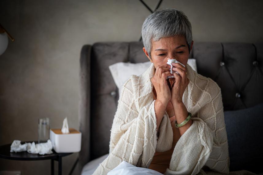 Woman blowing her nose in bed