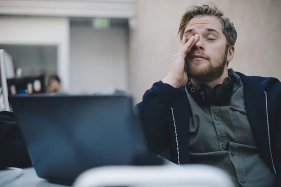 Tired office worker rubbing eyes while staring at computer screen